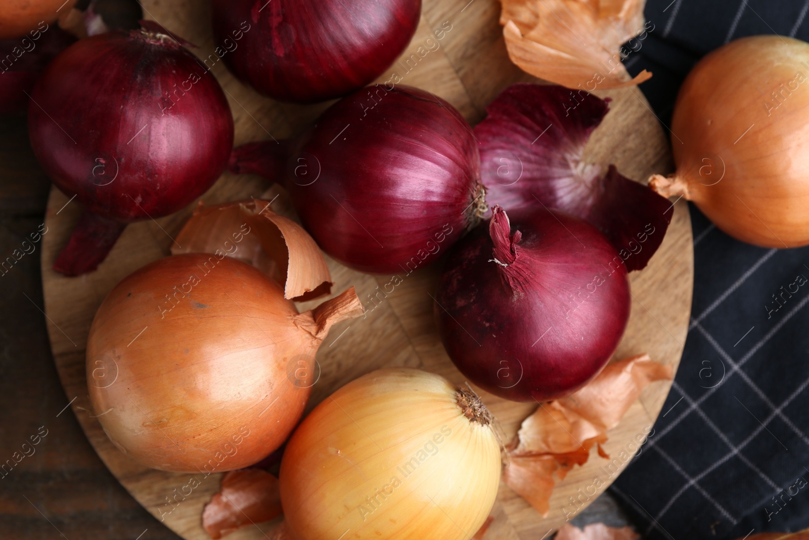 Photo of Fresh onions with peels on wooden table, top view