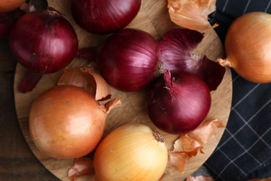 Photo of Fresh onions with peels on wooden table, top view