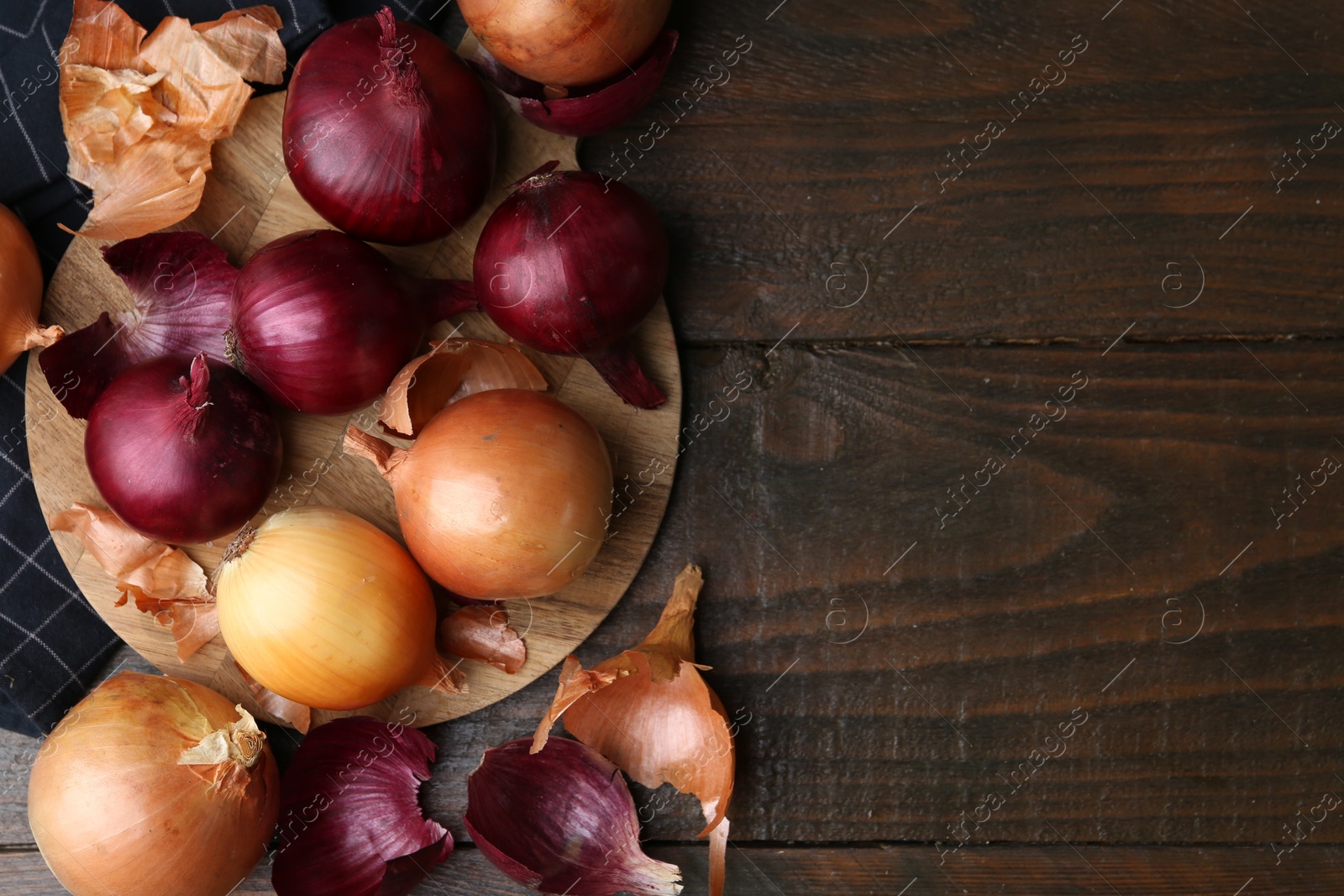 Photo of Fresh onions with peels on wooden table, flat lay. Space for text