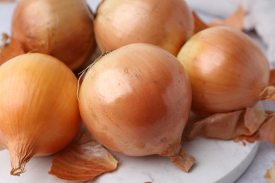 Photo of Fresh onions with peels on light table, closeup