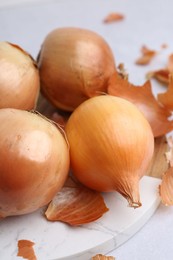 Photo of Fresh onions with peels on light table, closeup