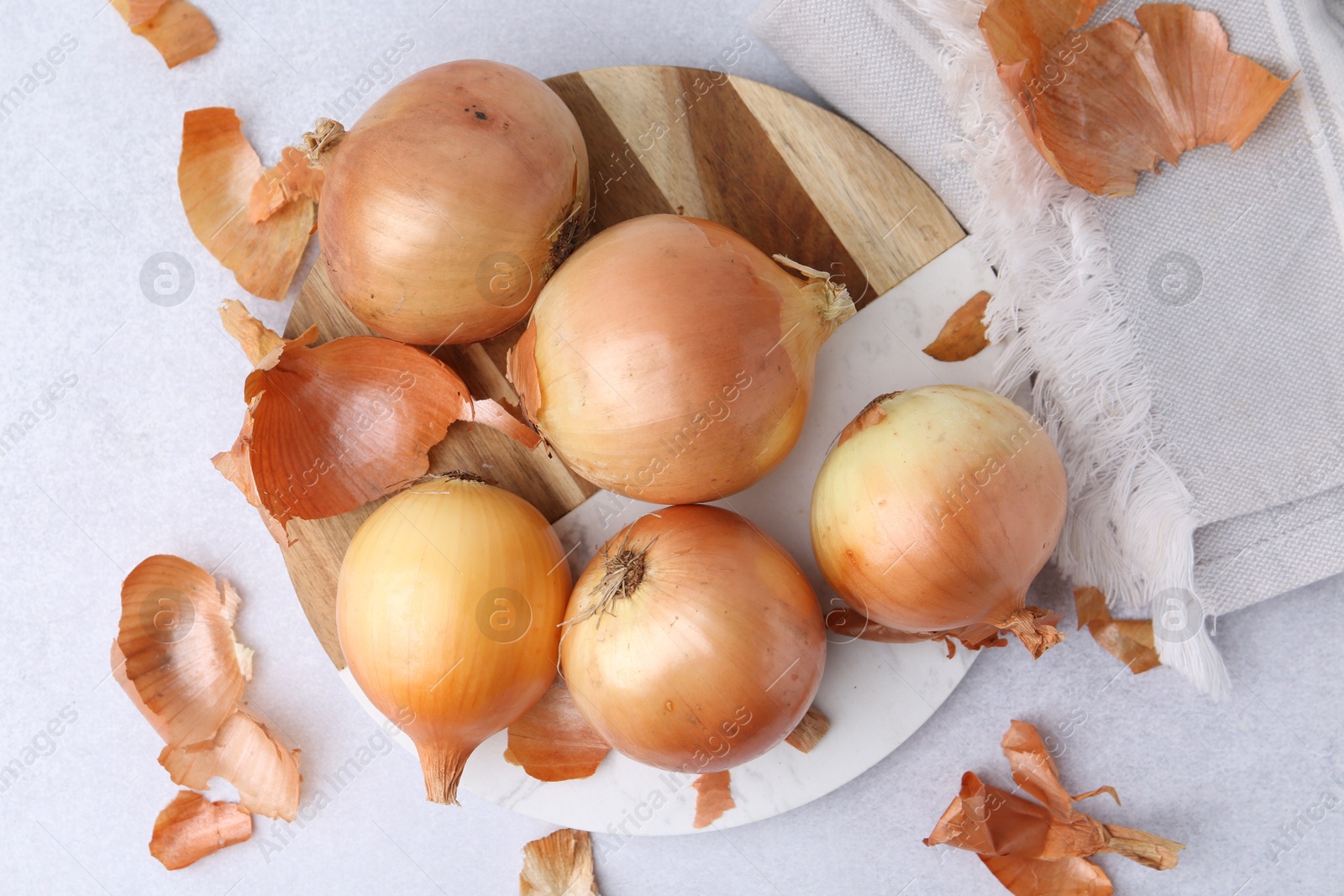 Photo of Fresh onions with peels on light table, flat lay