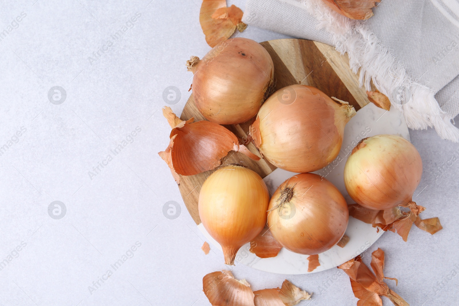 Photo of Fresh onions with peels on light table, flat lay. Space for text