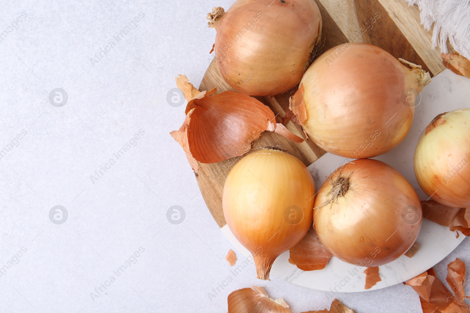 Photo of Fresh onions with peels on light table, flat lay. Space for text