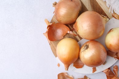 Photo of Fresh onions with peels on light table, flat lay. Space for text