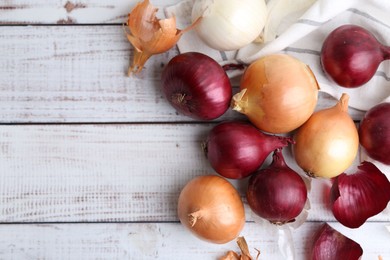 Photo of Fresh onions and peels on light wooden table, flat lay. Space for text