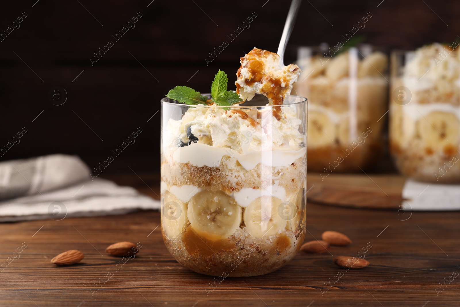 Photo of Taking tasty trifle dessert at wooden table, closeup