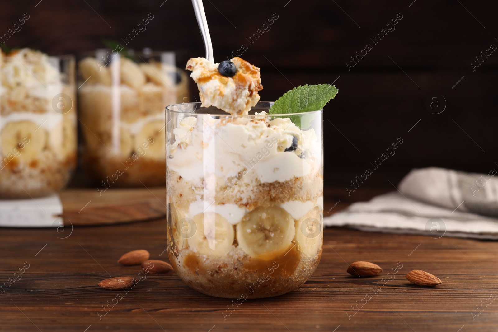 Photo of Taking tasty trifle dessert at wooden table, closeup