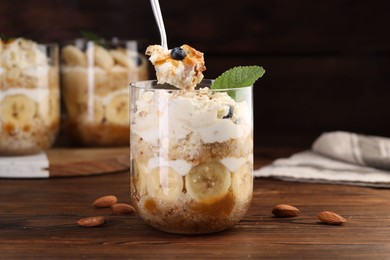 Photo of Taking tasty trifle dessert at wooden table, closeup