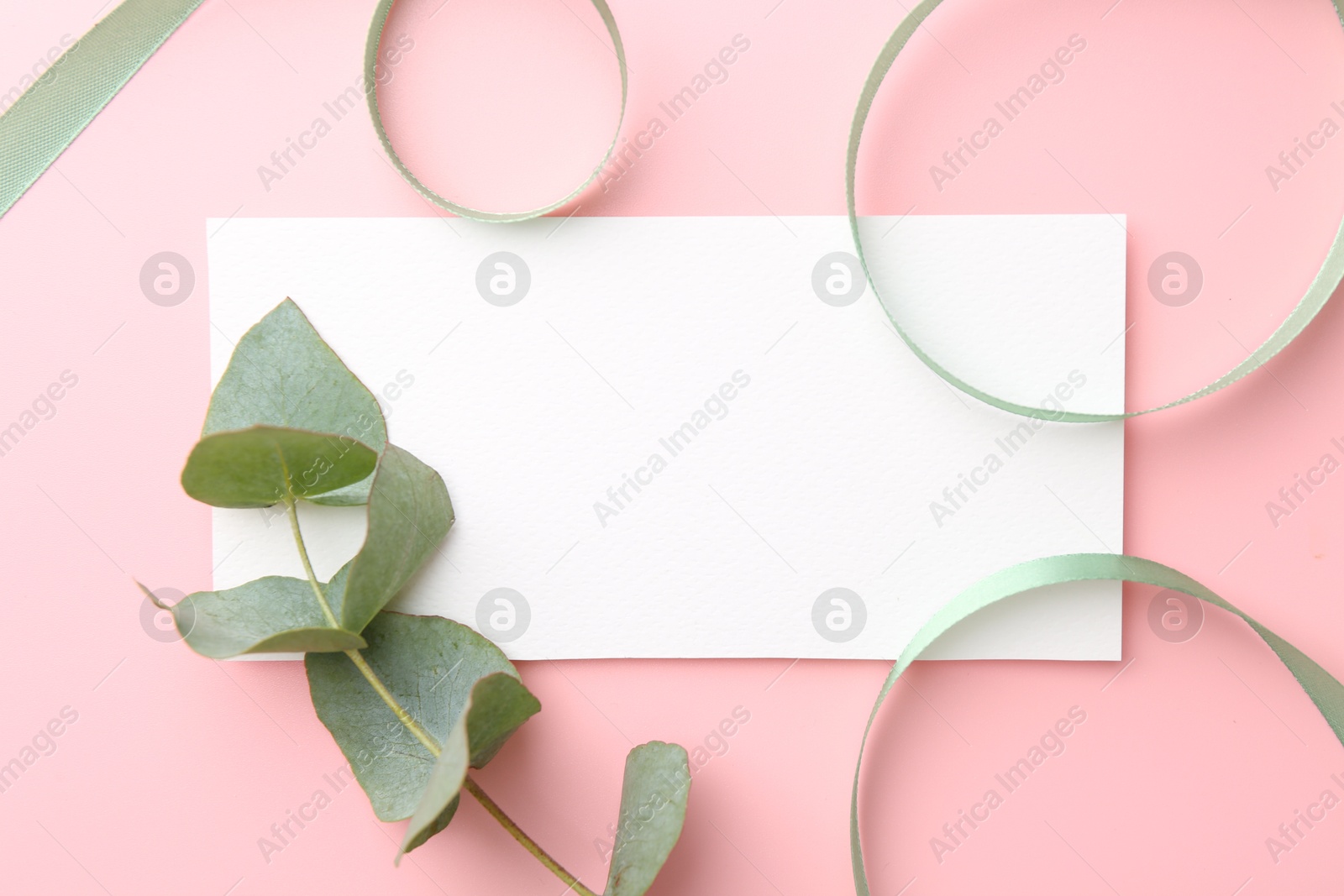 Photo of Blank card, ribbons and eucalyptus branch on pink background, flat lay