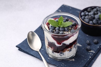 Photo of Tasty trifle dessert. Blueberries, sponge cake and whipped cream in glass on light grey table