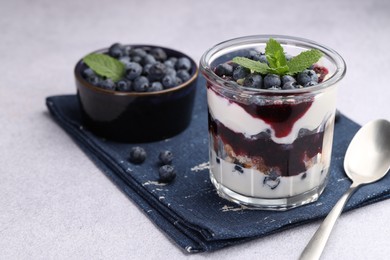 Photo of Tasty trifle dessert. Blueberries, sponge cake and whipped cream in glass on light grey table