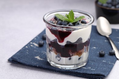 Photo of Tasty trifle dessert. Blueberries, sponge cake and whipped cream in glass on light grey table