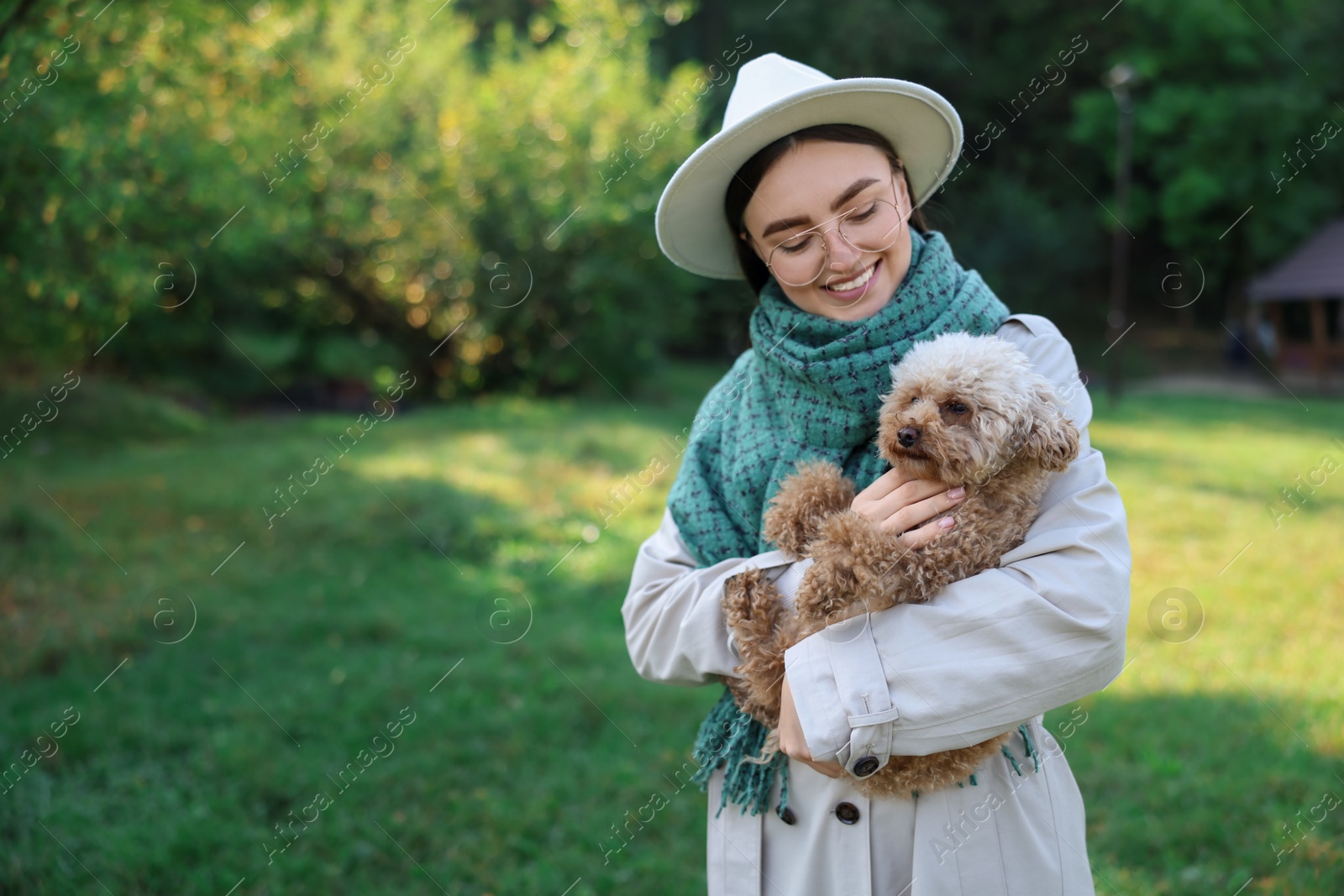 Photo of Smiling woman with cute dog in autumn park. Space for text