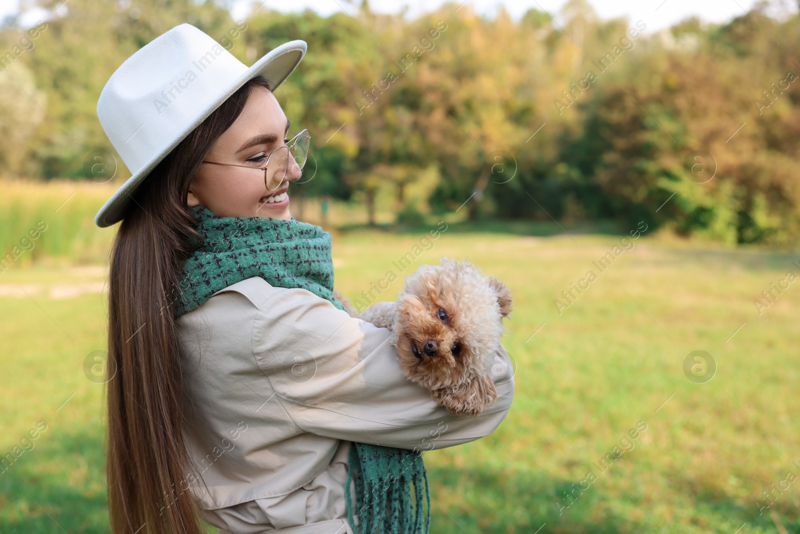 Photo of Smiling woman with cute dog in autumn park. Space for text