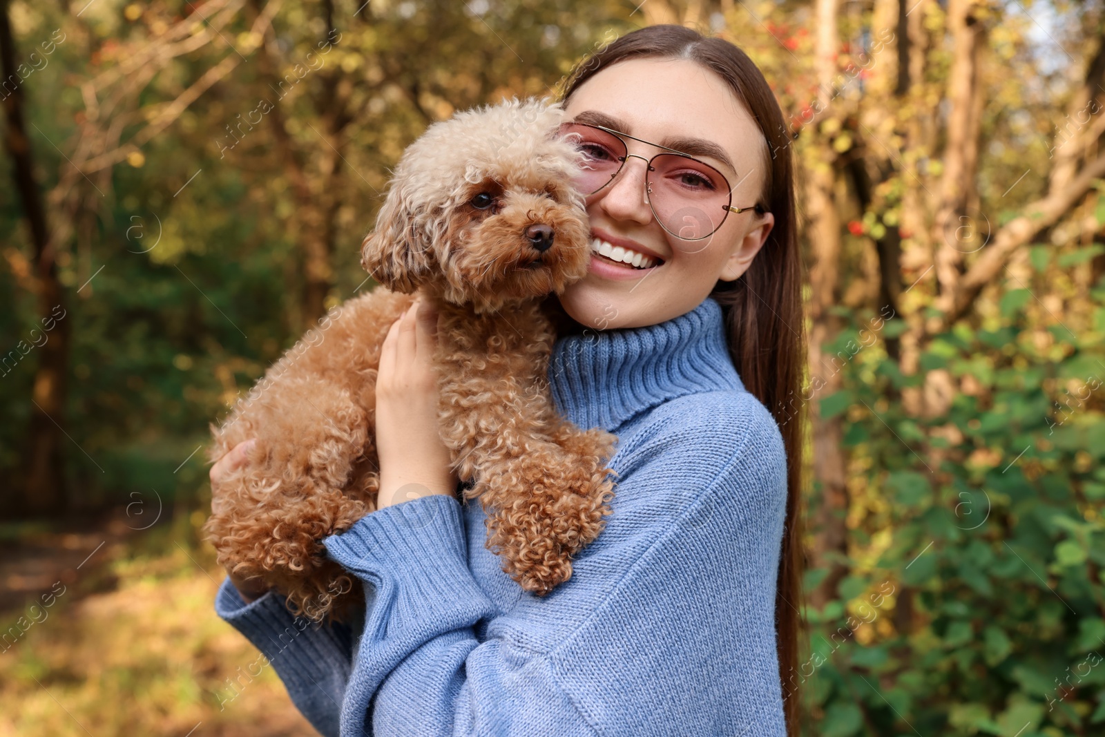 Photo of Smiling woman with cute dog in autumn park