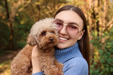 Smiling woman with cute dog in autumn park