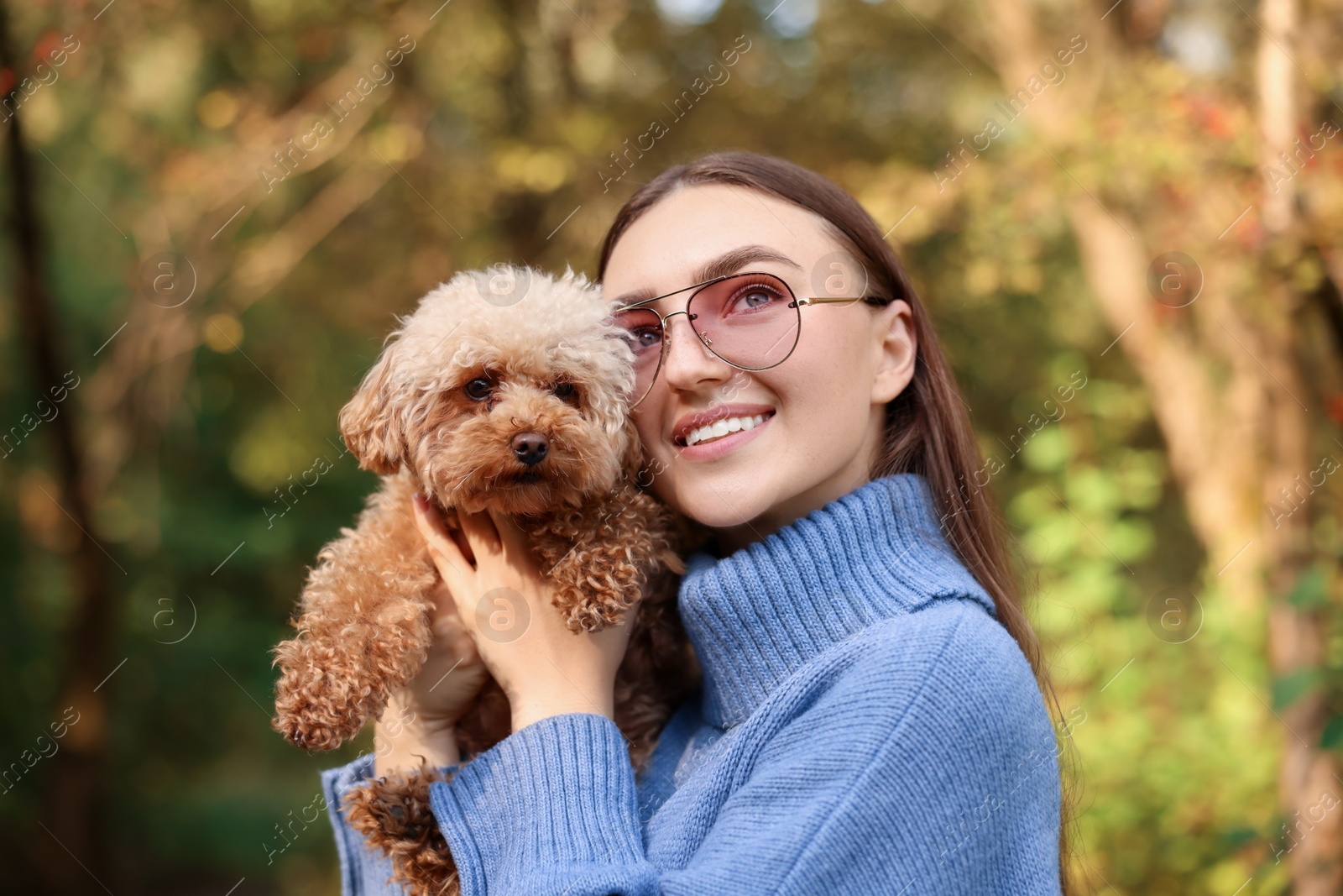 Photo of Smiling woman with cute dog in autumn park