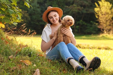 Smiling woman with cute dog in autumn park