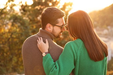 Cute couple enjoying autumn evening outdoors together, back view