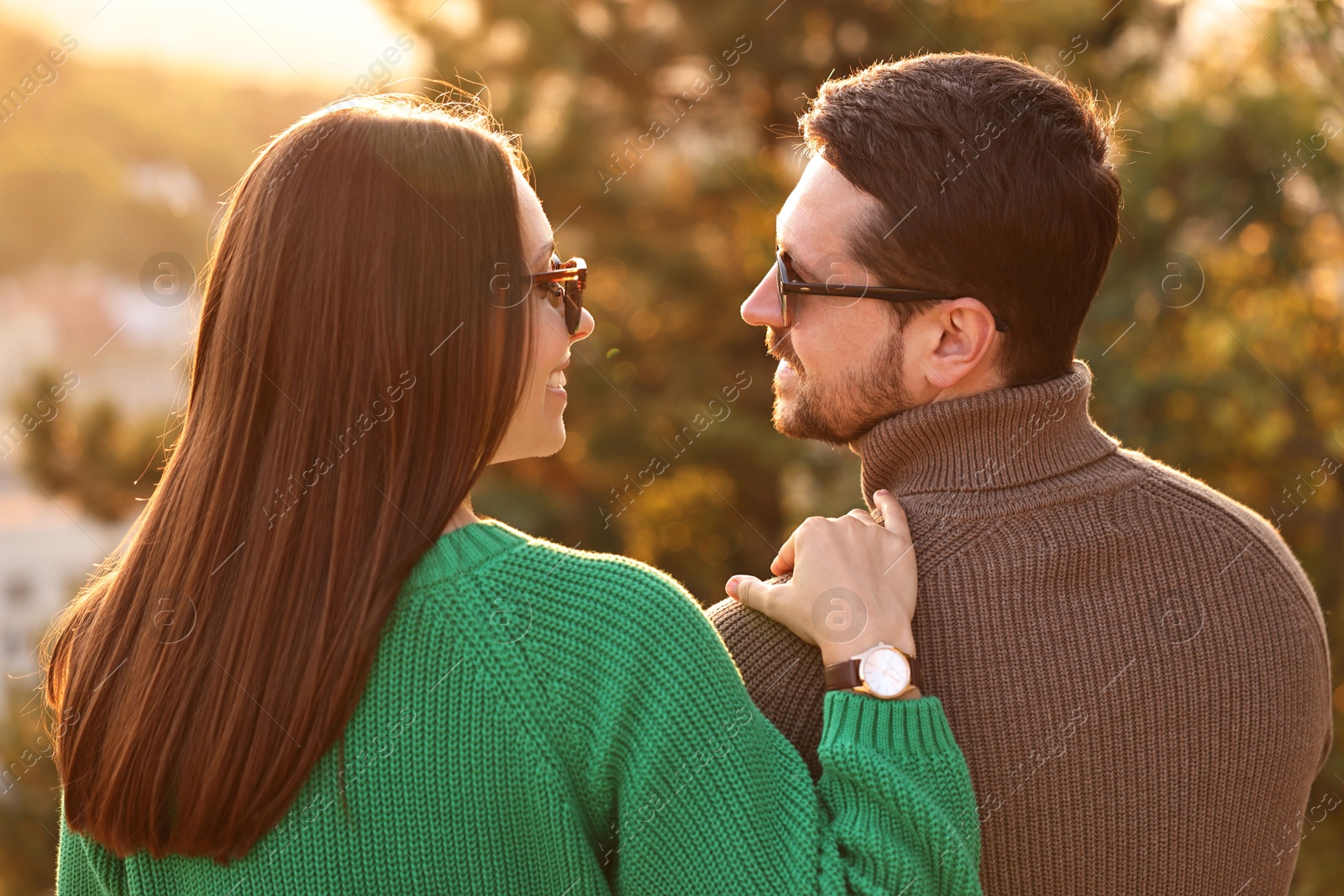 Photo of Cute couple enjoying autumn evening outdoors together, back view