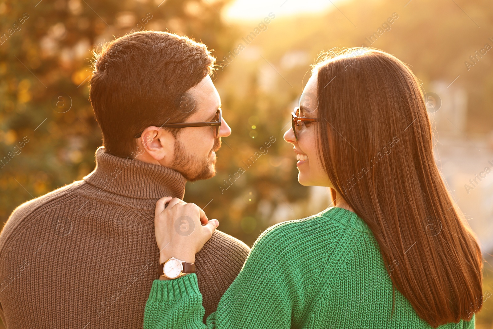 Photo of Cute couple enjoying autumn evening outdoors together, back view