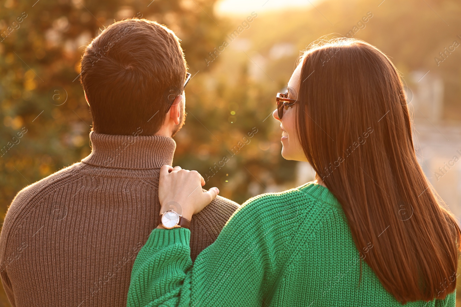 Photo of Cute couple enjoying autumn evening outdoors together, back view