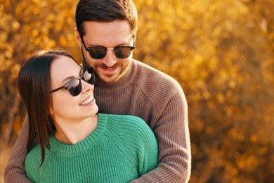 Photo of Beautiful couple hugging outdoors in autumn evening, space for text