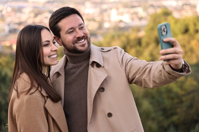 Beautiful couple taking selfie together outdoors on autumn day