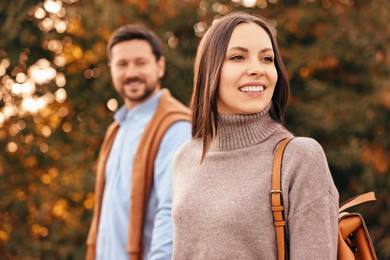 Beautiful couple walking together in park on autumn day, selective focus