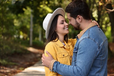 Photo of Beautiful couple hugging in park on autumn day, space for text