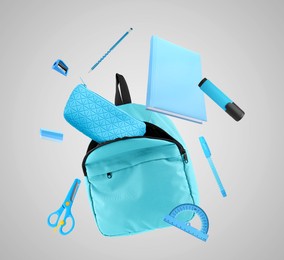 Image of Backpack and school stationery in air on light grey background