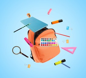 Image of Orange backpack and school stationery in air on light blue background