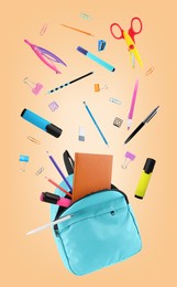 Image of Light blue backpack and school stationery in air on pale orange background