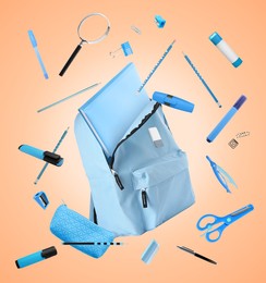 Image of Light blue backpack and school stationery in air on pale coral background