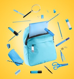 Light blue backpack and school stationery in air on golden background