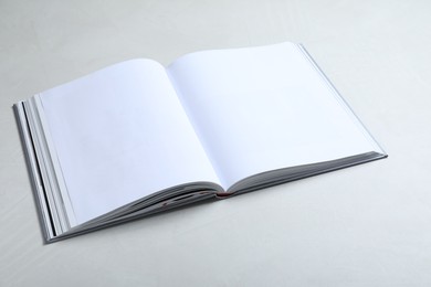 Photo of Open book with hard cover on light grey table