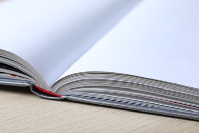 Open book with hard cover on wooden table, closeup