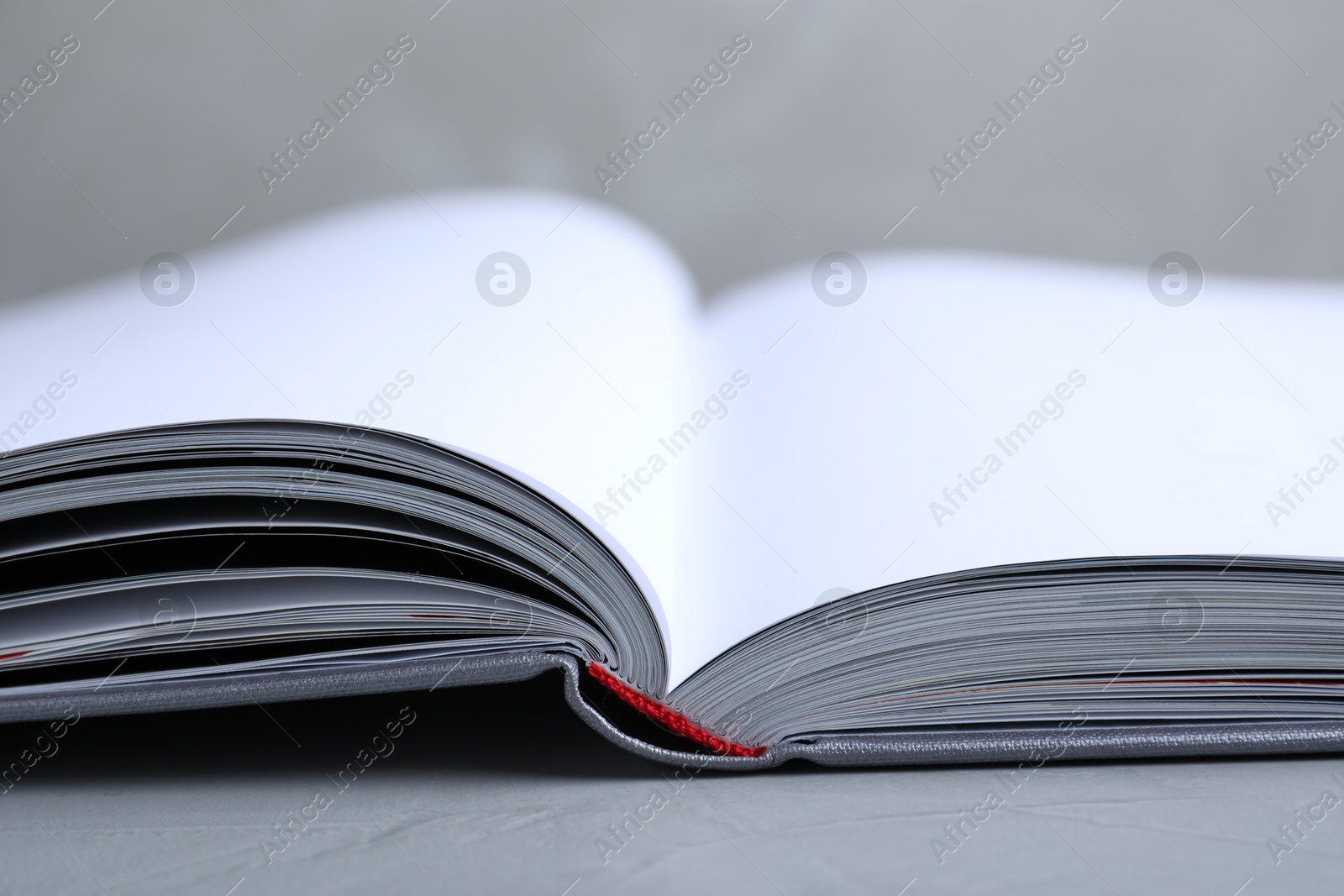 Photo of Open book with hard cover on grey table, closeup