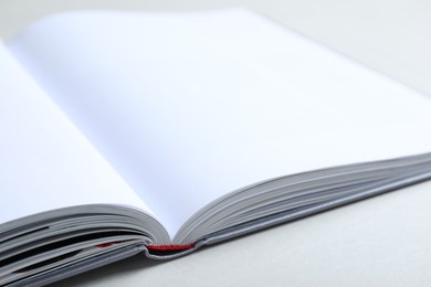 Photo of Open book with hard cover on light grey table, closeup