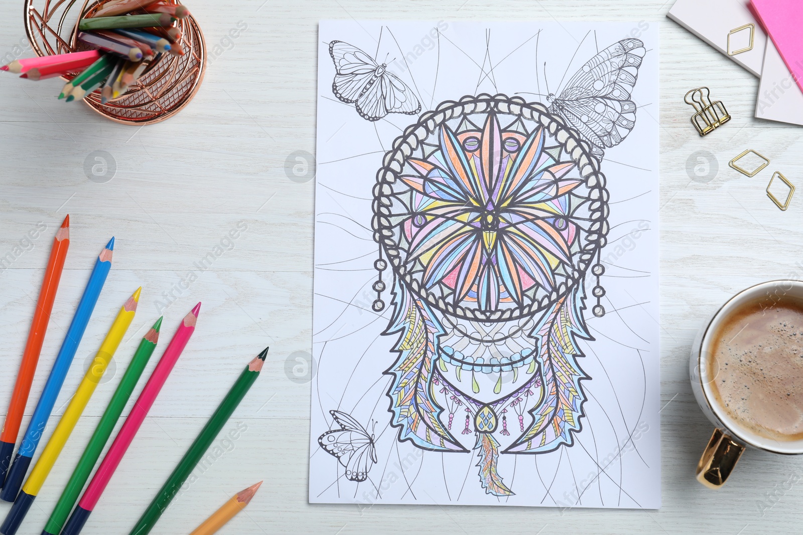 Photo of Antistress coloring page, pencils and coffee on white wooden table, flat lay