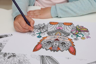 Photo of Little girl coloring antistress page at table, closeup