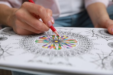 Photo of Young woman coloring antistress page, closeup view