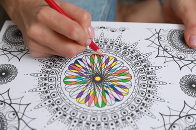 Photo of Young woman coloring antistress page, closeup view