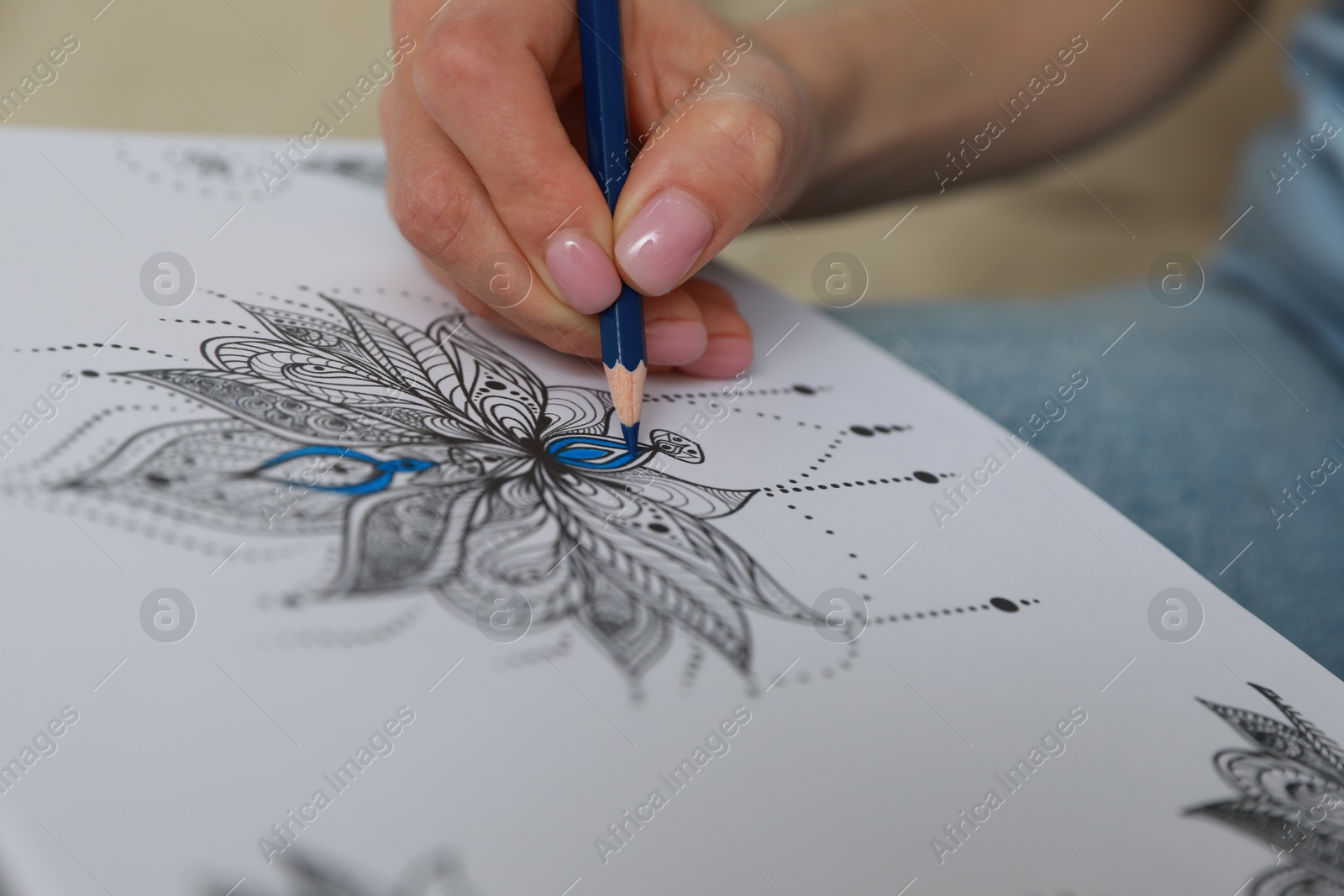 Photo of Young woman coloring antistress page on blurred background, closeup