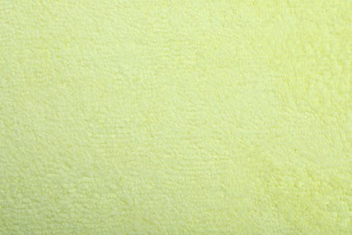 Pale yellow microfiber cloth as background, top view