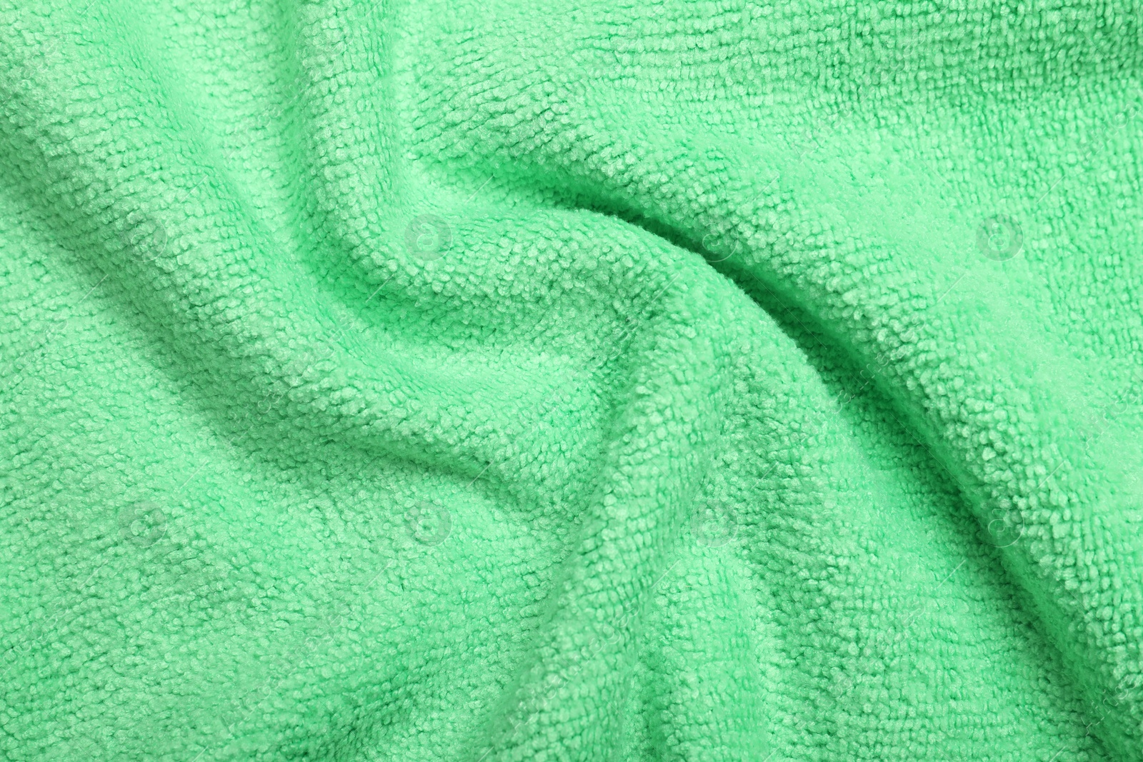 Photo of Crumpled light green microfiber cloth as background, closeup