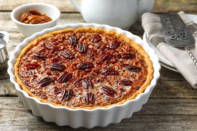 Delicious pecan pie in baking dish on wooden table, closeup