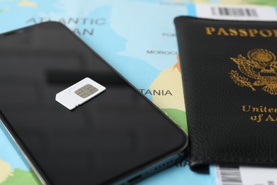 SIM card, smartphone and passport on world map, closeup