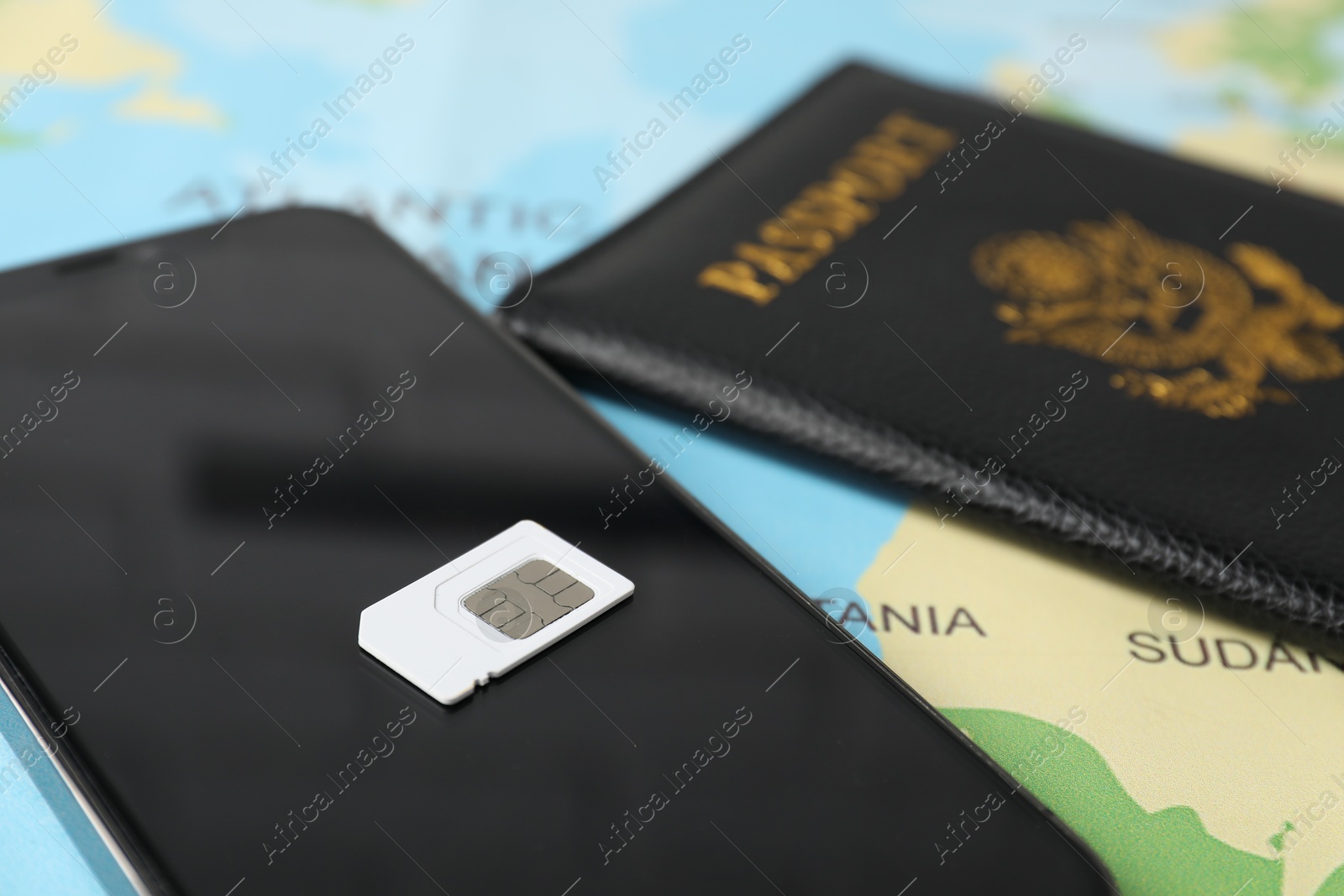 Photo of SIM card, smartphone and passport on world map, closeup